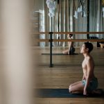 A shirtless man practicing yoga poses in a serene studio environment, reflecting wellness and tranquility.