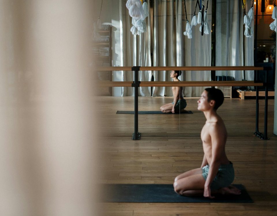 A shirtless man practicing yoga poses in a serene studio environment, reflecting wellness and tranquility.