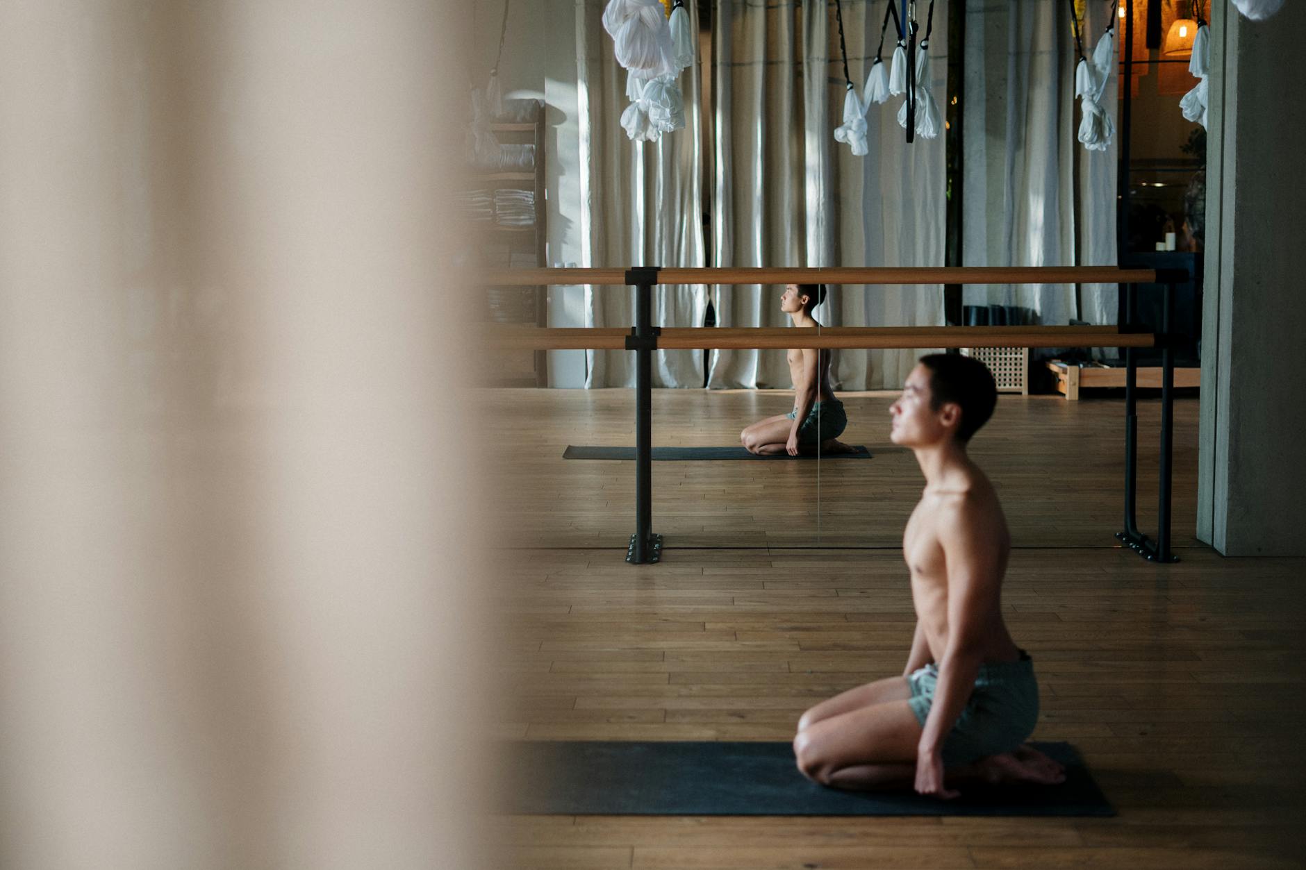 A shirtless man practicing yoga poses in a serene studio environment, reflecting wellness and tranquility.