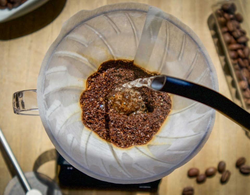 Overhead angle of pour over coffee with fresh grounds and hot water in a glass carafe.