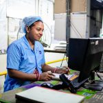 Female factory worker inputs data in a textile manufacturing setting. Indoors and focused.