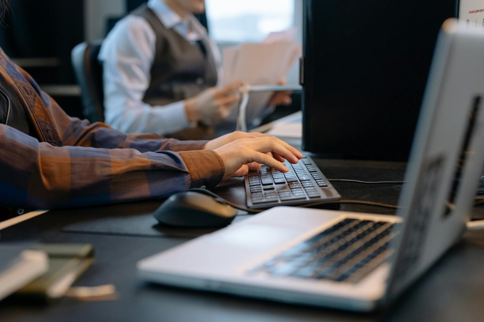 Close-up of office workers engaged in a tech project at a modern workplace.