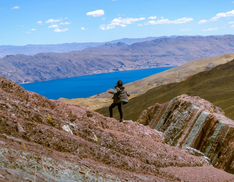 Hiker explores stunning mountain landscape near Layo, Cuzco with vibrant lake and rugged terrain.