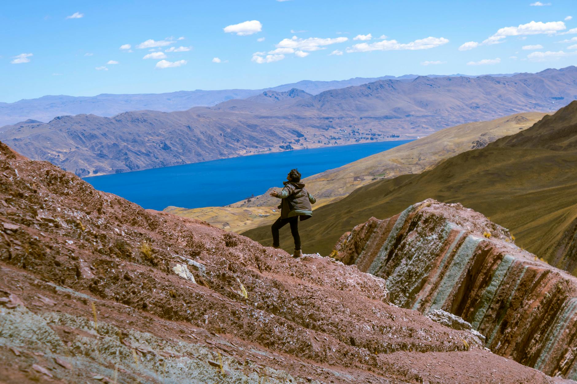 Hiker explores stunning mountain landscape near Layo, Cuzco with vibrant lake and rugged terrain.