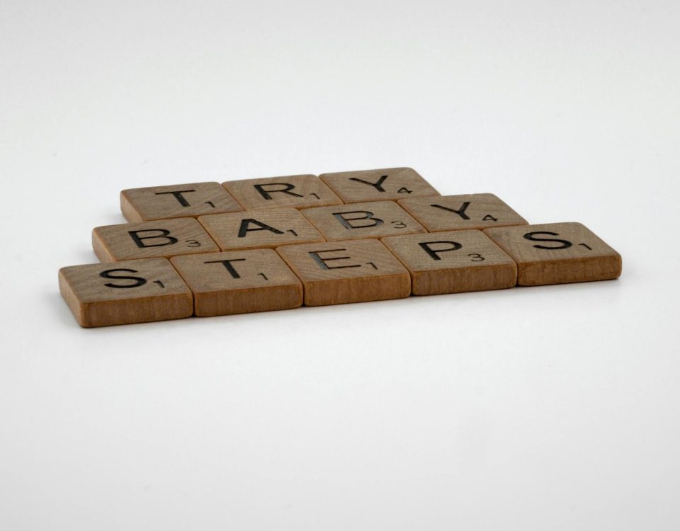 Scrabble tiles forming the phrase 'Try Baby Steps' on a white background.
