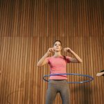 Three women exercising with hula hoops indoors promoting fitness and fun.