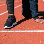 Runner in crouched starting position on track, ready to sprint.