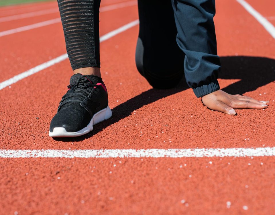 Runner in crouched starting position on track, ready to sprint.